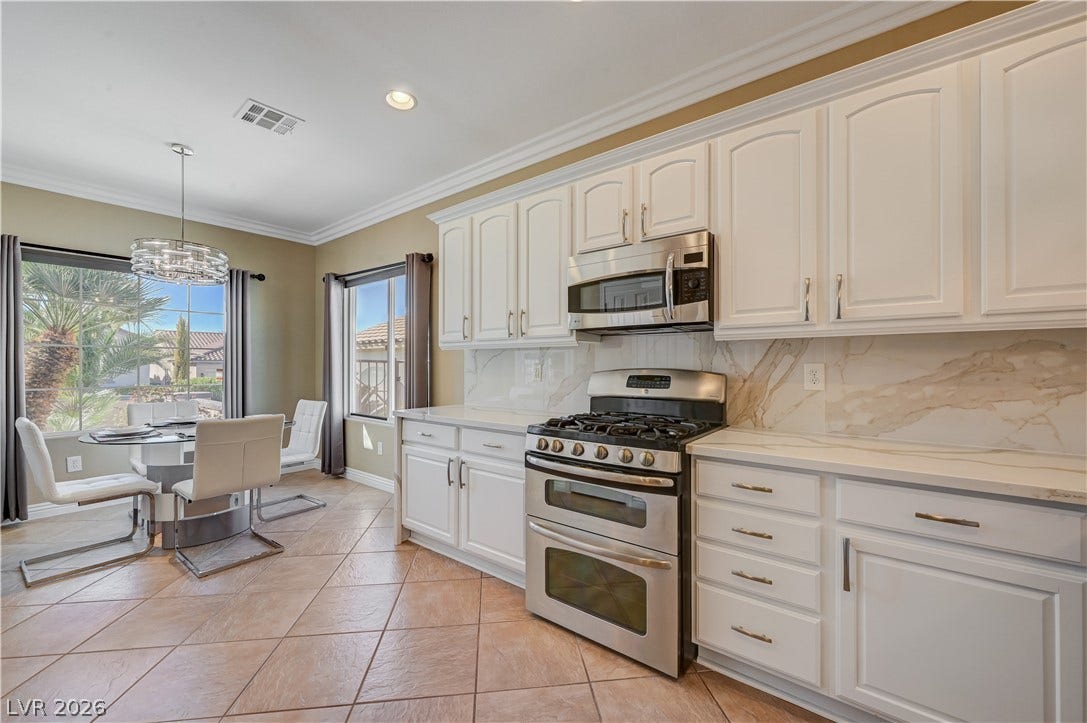 Elegant crown molding complements classic raised-panel cabinetry and stone countertops in this functional culinary space.