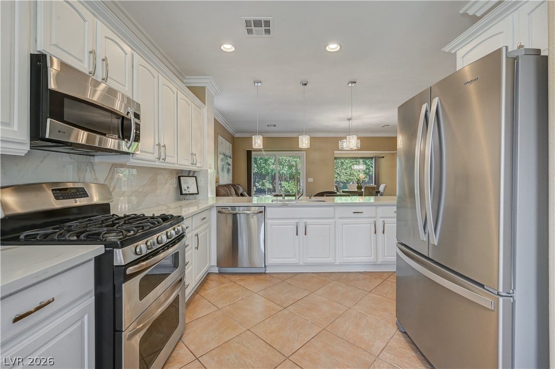 Gleaming stone countertops and classic crown molding elevate this open-concept culinary space.