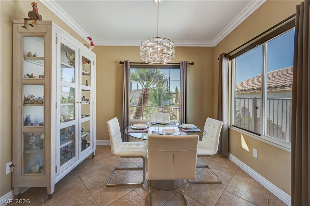 Elegant crown molding and classic tile flooring frame a sunlit dining area with neighborhood views.