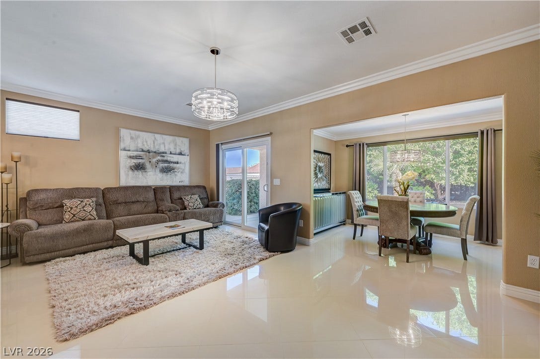 Polished tile flooring and crown molding highlight this seamless, open living and dining area.