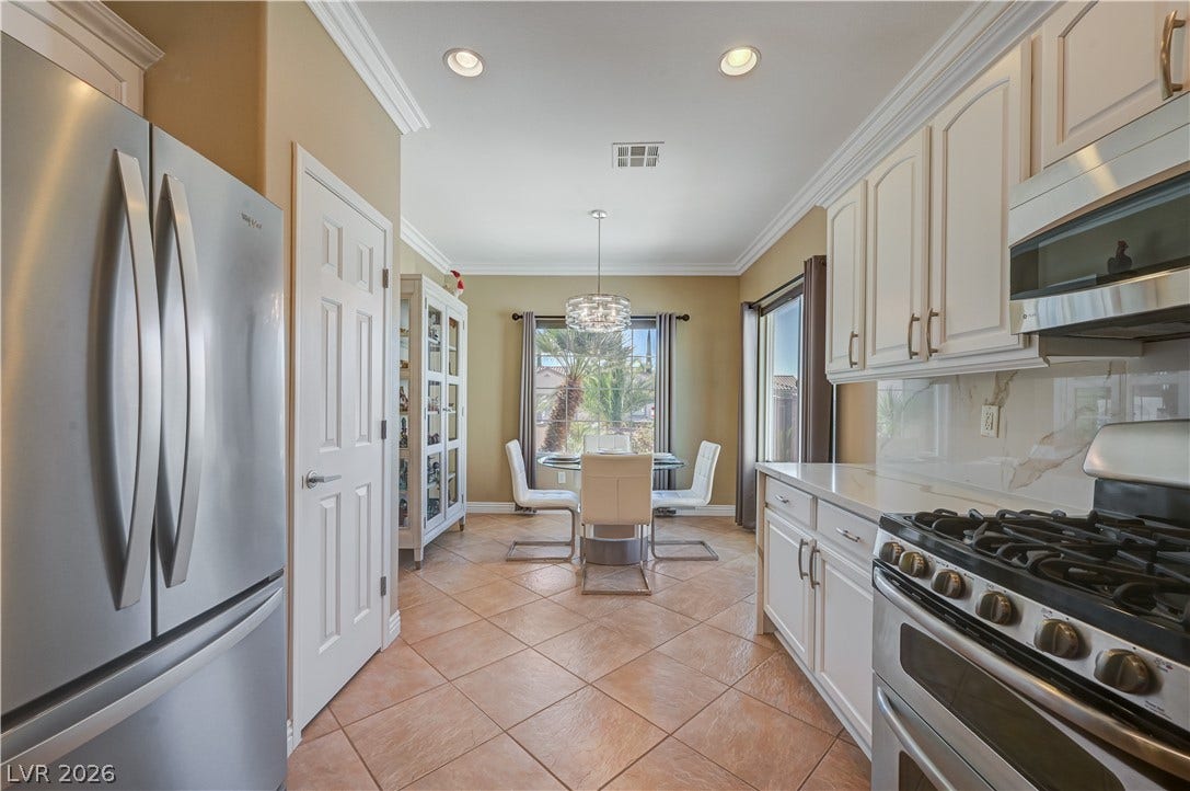 Tiled flooring and crown molding frame this kitchen with its adjoining casual dining space.