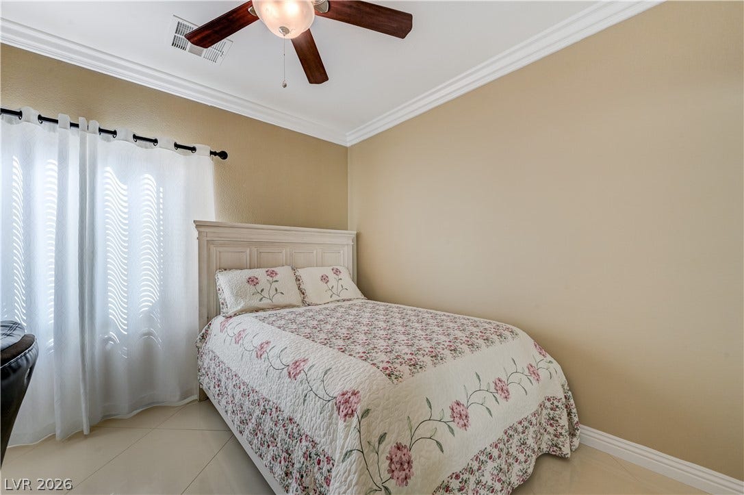 Elegant crown molding and polished tile floors frame this comfortable bedroom space.