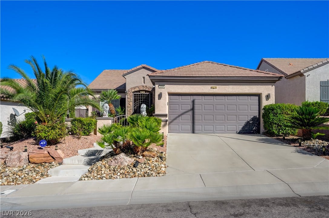 A wide concrete driveway leads to the garage of this tile-roofed desert home.
