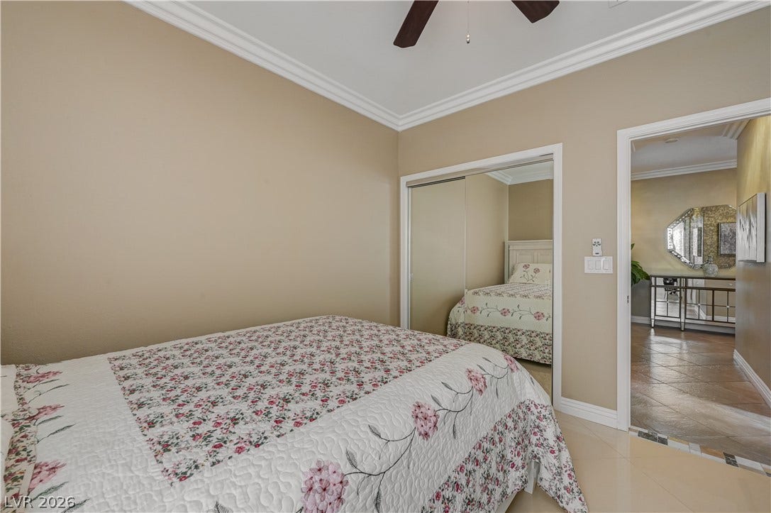 Polished tile flooring and elegant crown molding elevate this serene bedroom space.