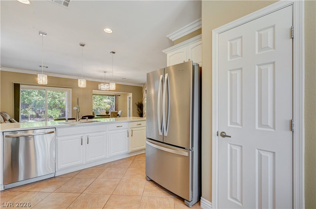 Tiled flooring and crown molding accent this open kitchen equipped with stainless steel appliances.