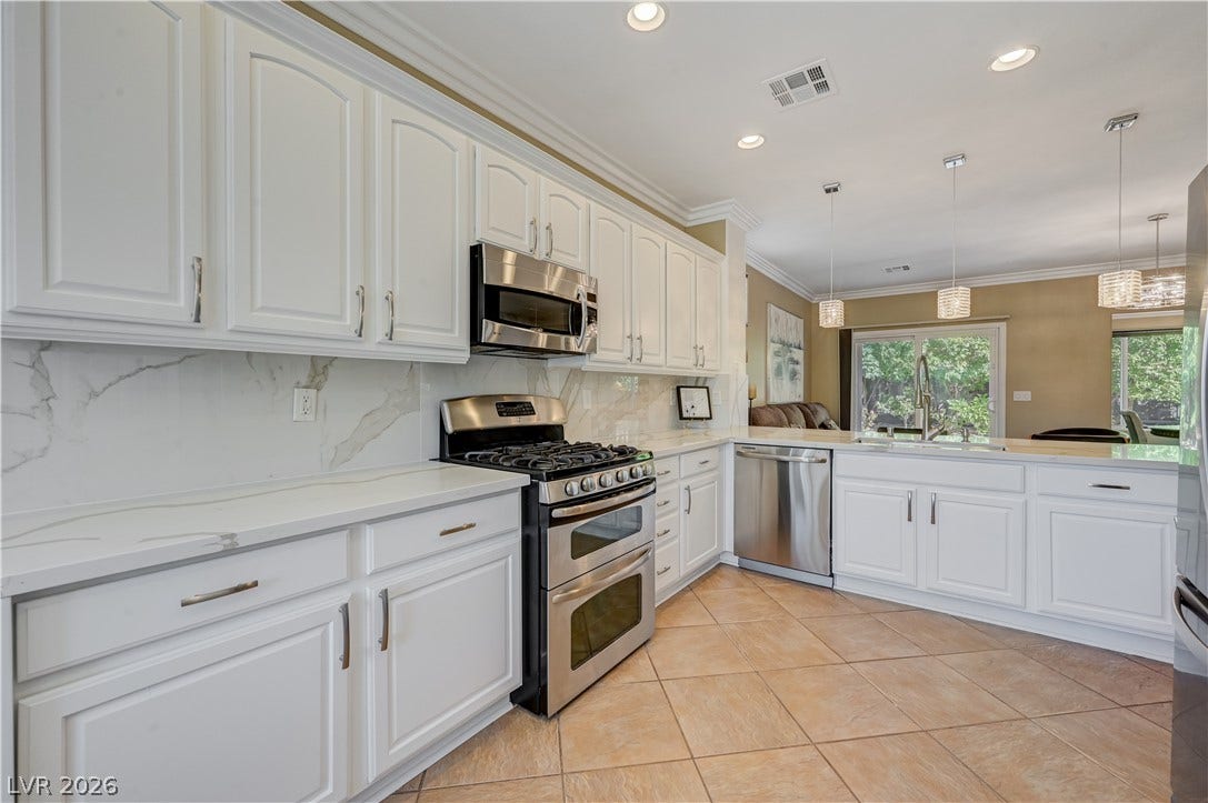 Bright tile floors complement classic raised-panel cabinetry and stone countertops in this modern workspace.