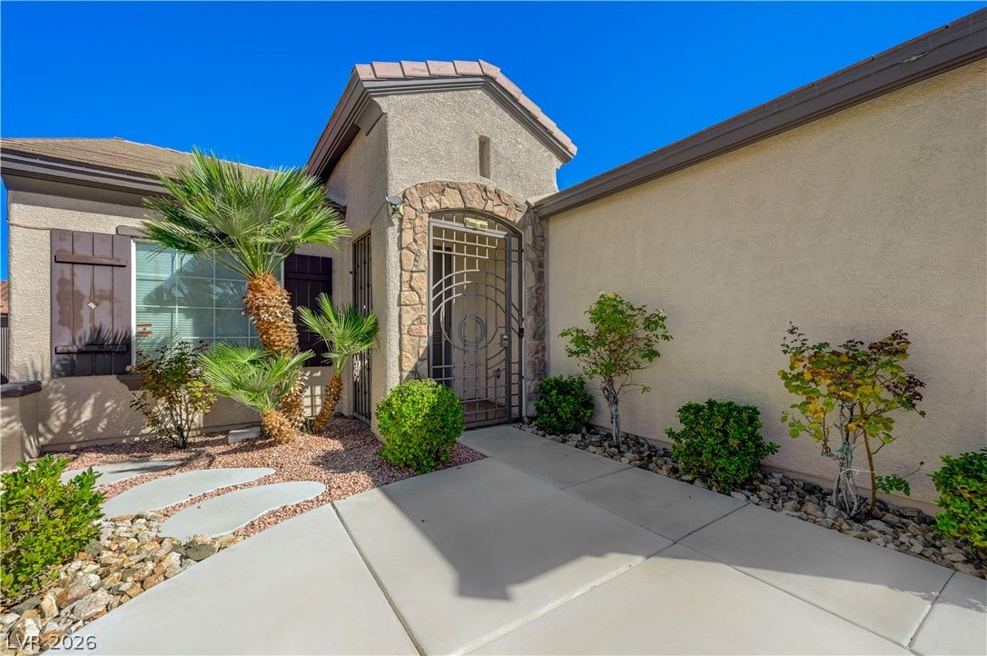 An inviting gated courtyard entrance welcomes visitors with manicured desert landscaping and stone details.