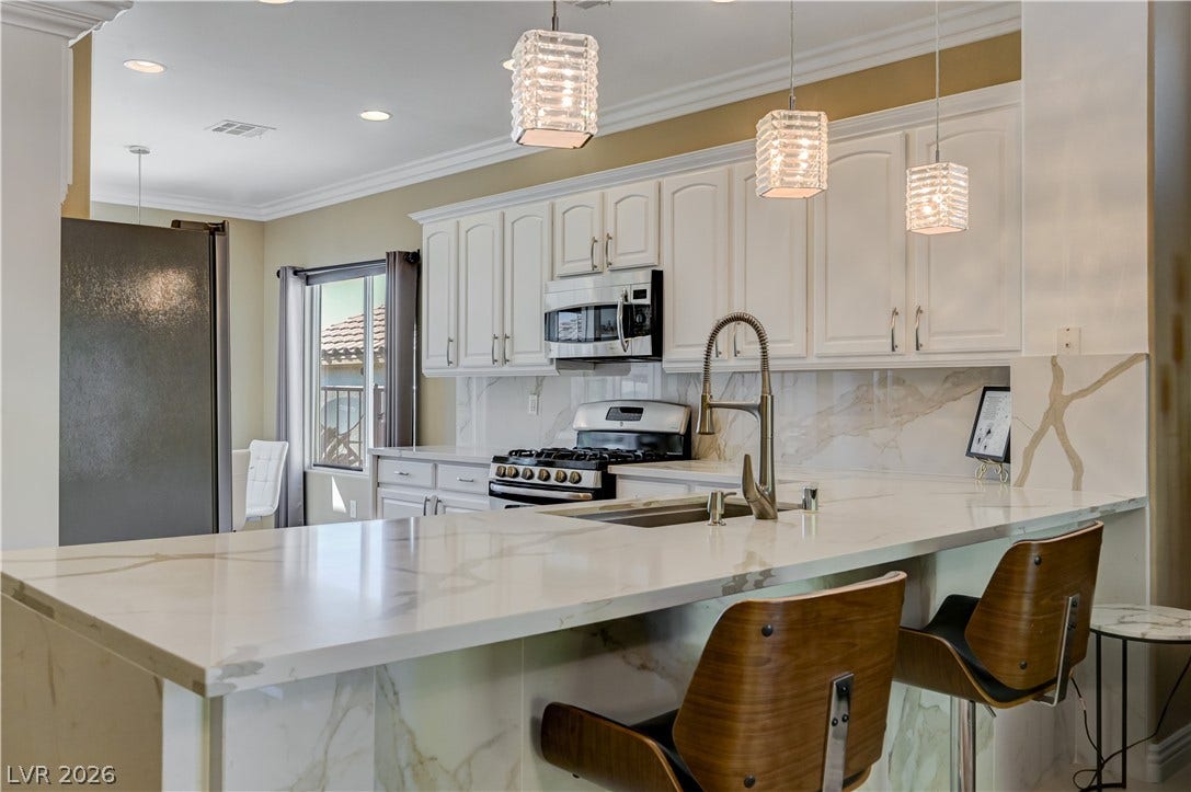 Elegant stone countertops and crisp white cabinetry define this beautifully illuminated modern kitchen space.