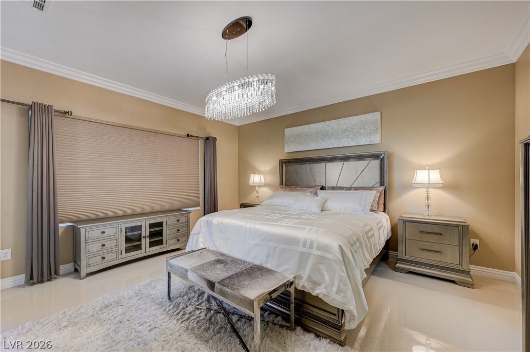 Polished tile flooring and crisp crown molding elevate this refined bedroom retreat.