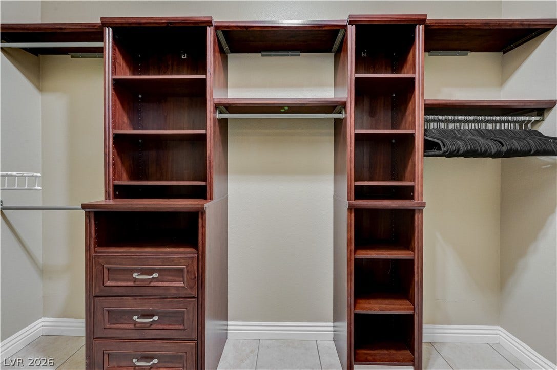 Rich wood built-ins and tile flooring maximize storage in this spacious walk-in closet.