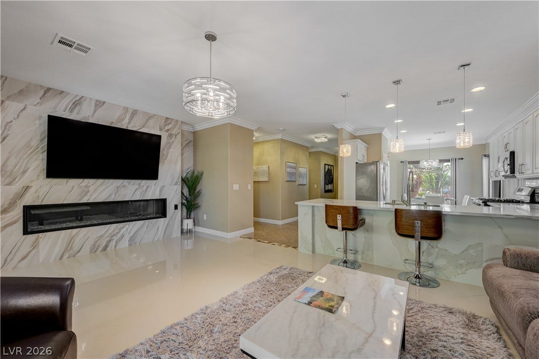 An open floorplan seamlessly connects the living space to the kitchen with polished tile floors.