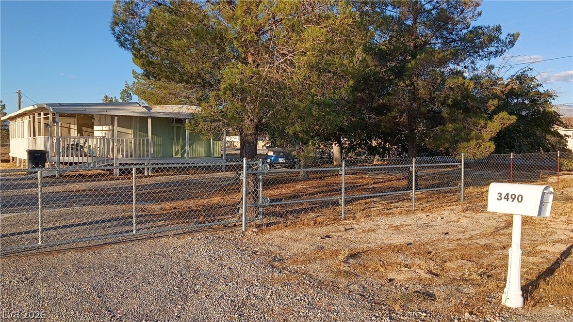 3490 E Savoy Boulevard, Pahrump, NV 89061 Mature trees shade the fenced yard of this property featuring a covered porch.