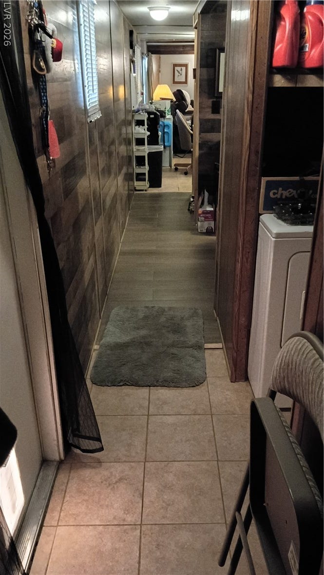 3490 E Savoy Boulevard, Pahrump, NV 89061 Rich wood paneling and durable tile flooring define this long, functional hallway space.