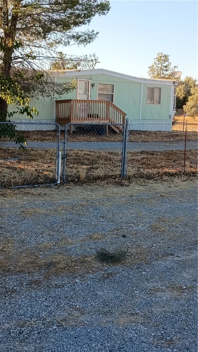 3490 E Savoy Boulevard, Pahrump, NV 89061 A gravel driveway leads to a fenced yard and elevated front deck.