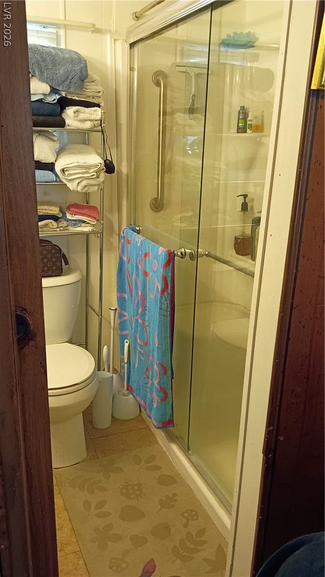 3490 E Savoy Boulevard, Pahrump, NV 89061 Glazed sliding doors enclose a practical walk-in shower unit next to a compact toilet niche.