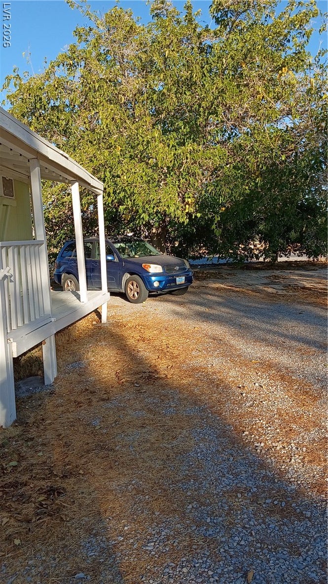 3490 E Savoy Boulevard, Pahrump, NV 89061 Mature trees shade the gravel driveway and elevated front porch structure.