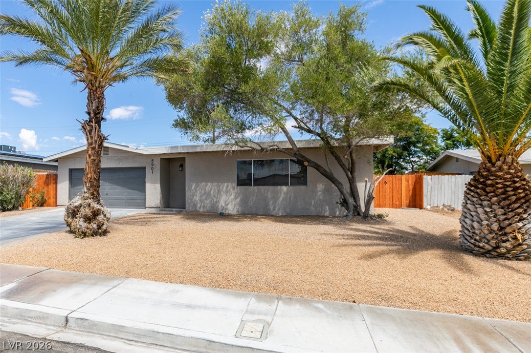 Palm trees flank the low-maintenance desert front yard of this classic single-story stucco home.