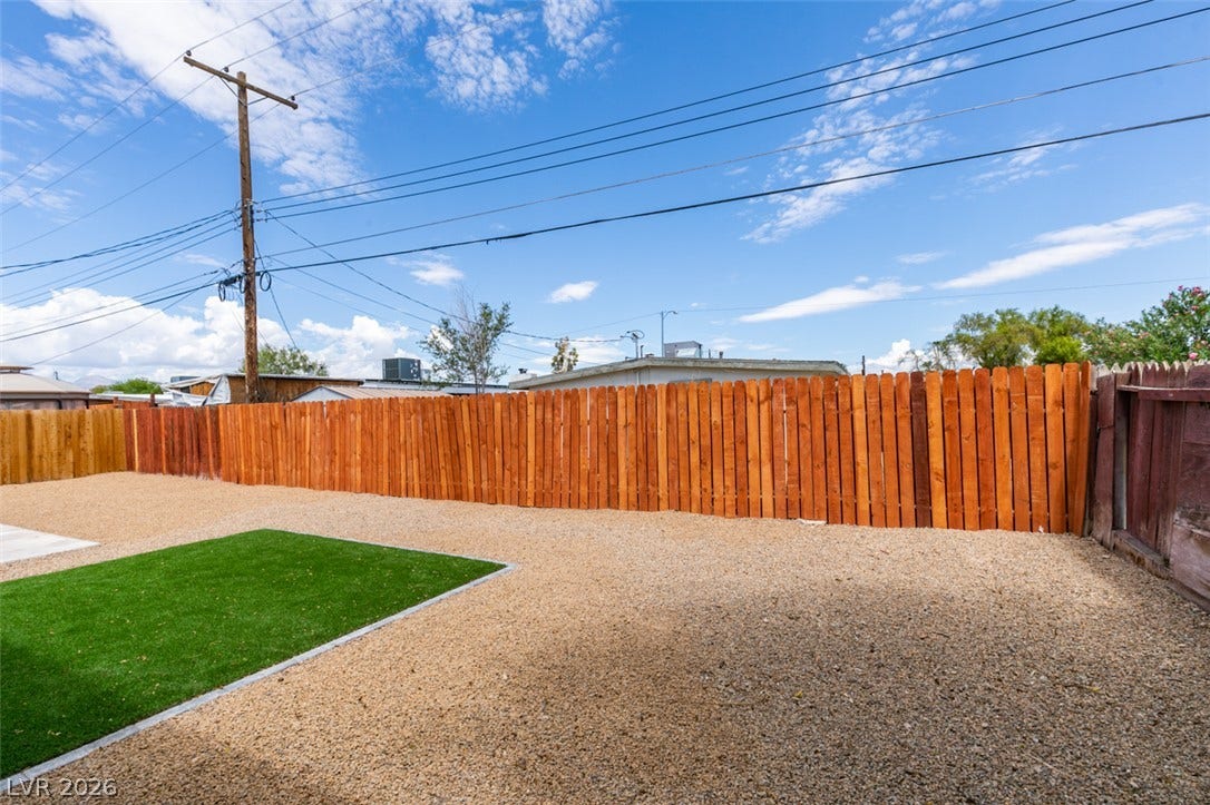 Enclosed wood fencing defines the low-maintenance gravel yard under wide open skies.