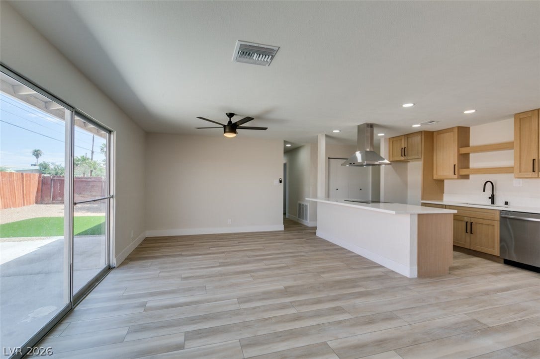 An open floor plan connects the living area with a modern kitchen featuring sliding glass doors.