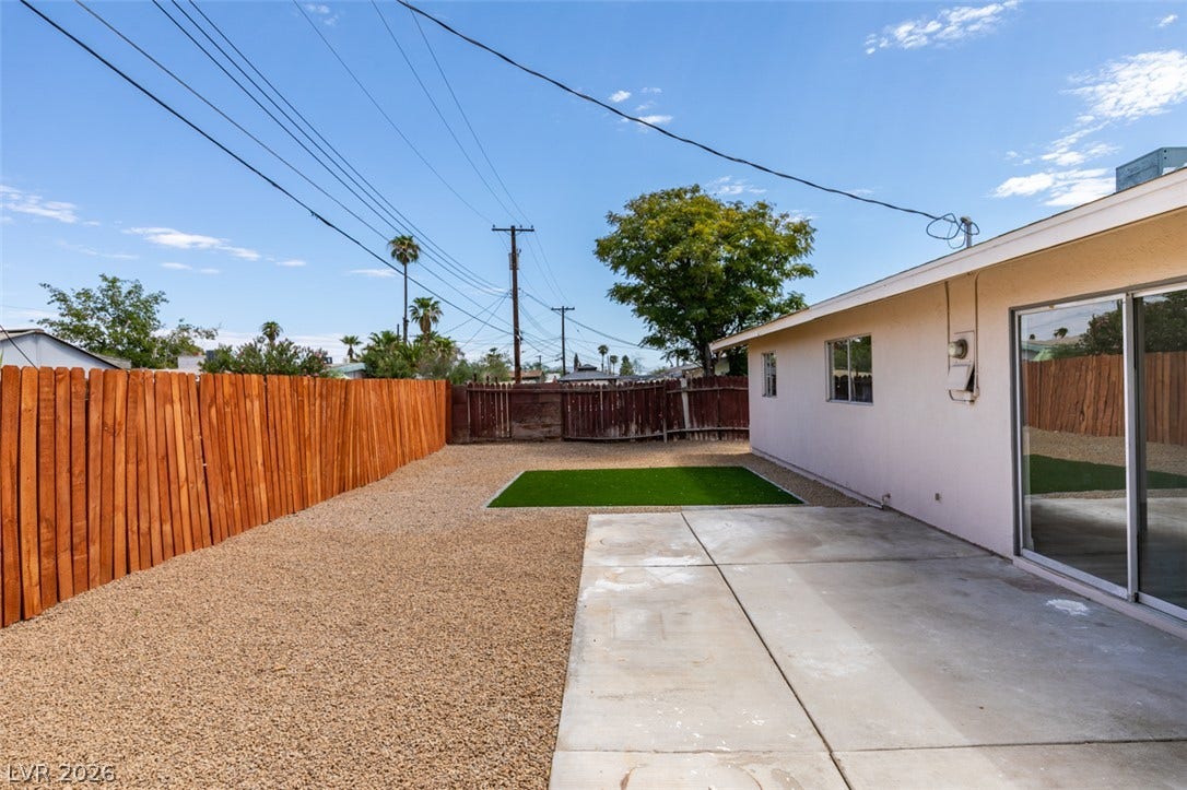 A spacious backyard features low-maintenance gravel landscaping and a concrete patio.