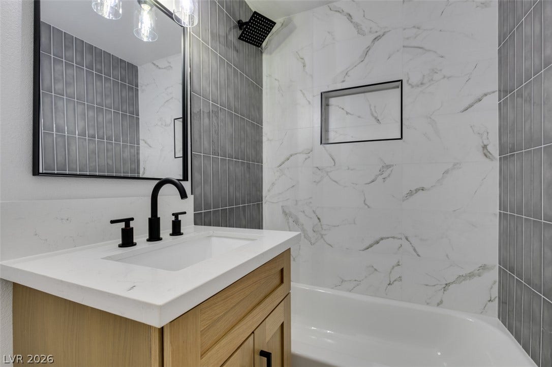 Exquisite marble-patterned shower surround complements the contemporary vanity and sleek black fixtures.