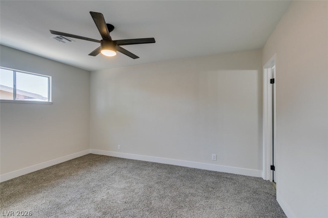 Plush carpeting and clean baseboards define this minimalist secondary bedroom space.