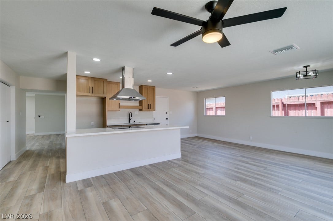 Smooth wood-look flooring anchors a modern open-concept space connected to a pristine kitchen area.