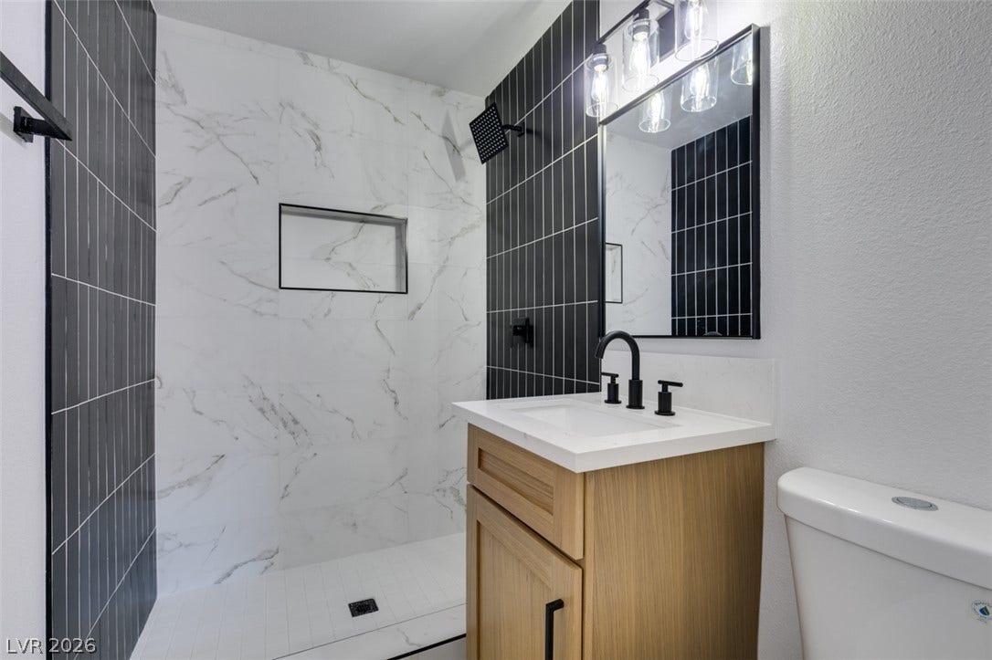 High-contrast wall tile and a modern wood vanity define this sleek, updated bathroom.
