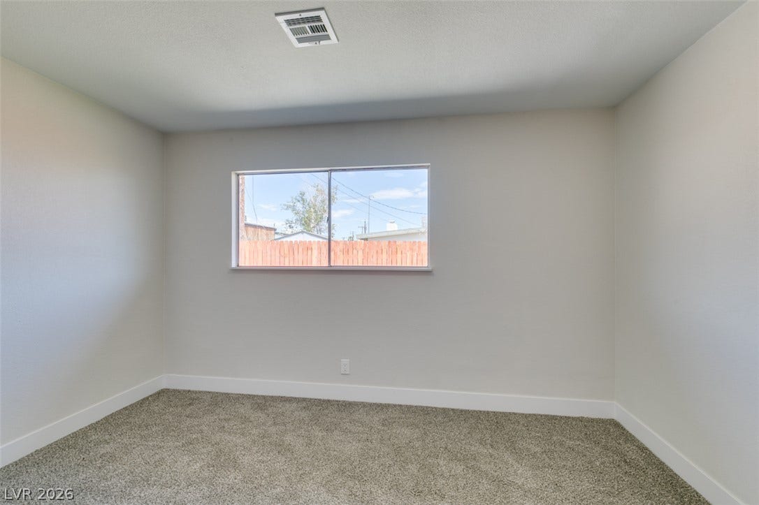 Plush carpeting anchors this clean-lined bedroom under a classic smooth ceiling.