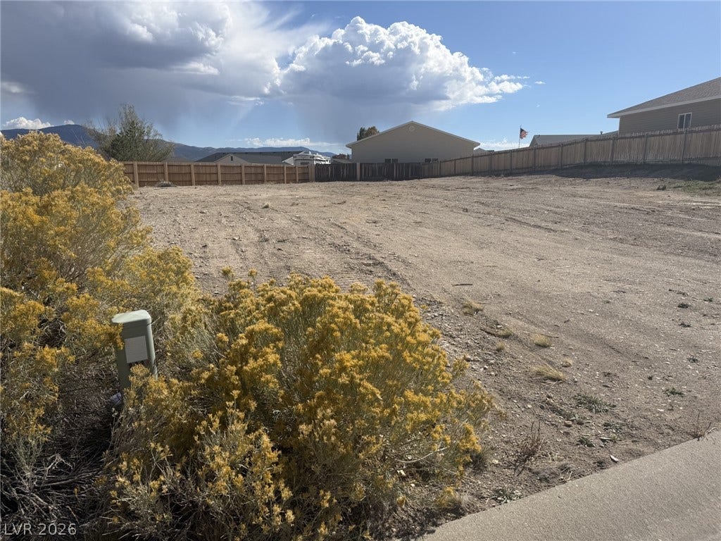 2248 Iron Drive, Ely, NV 89301 An open building lot features a wooden privacy fence and mountain views.