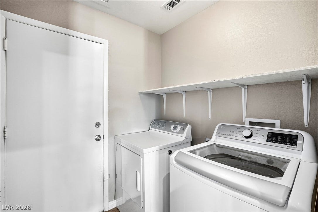 An organized utility space features overhead shelving above side-by-side laundry units.