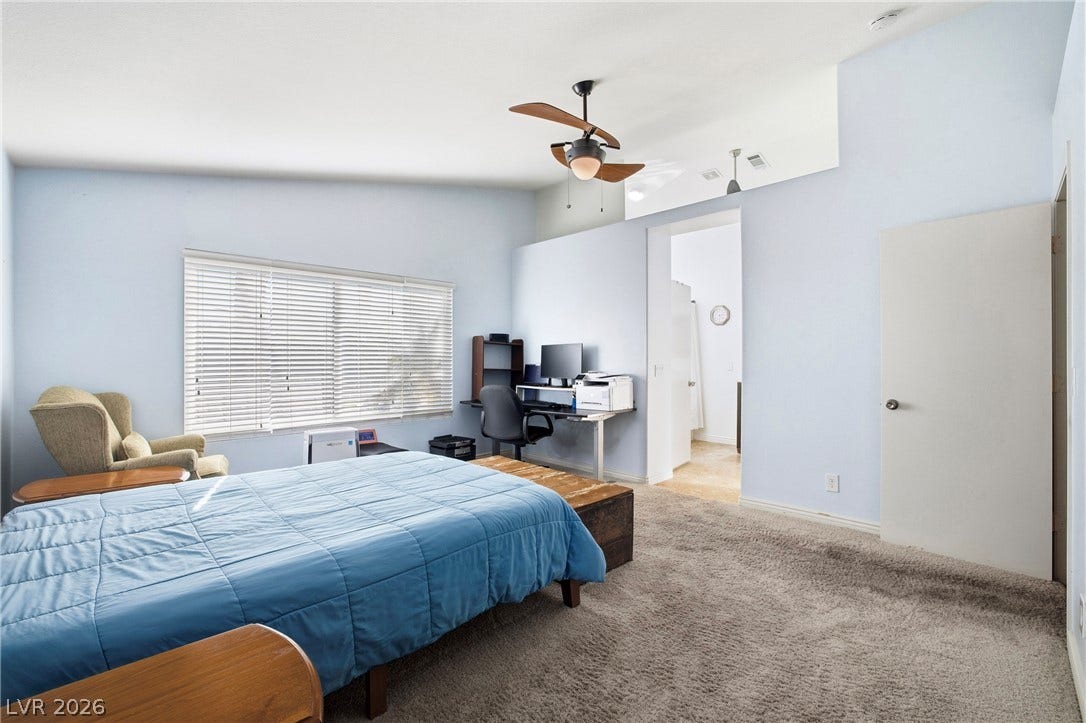 A spacious primary bedroom features comfortable plush carpeting and high vaulted ceilings.