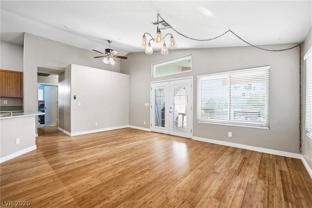 Rich wood flooring anchors this living space beneath high vaulted ceilings and French doors.