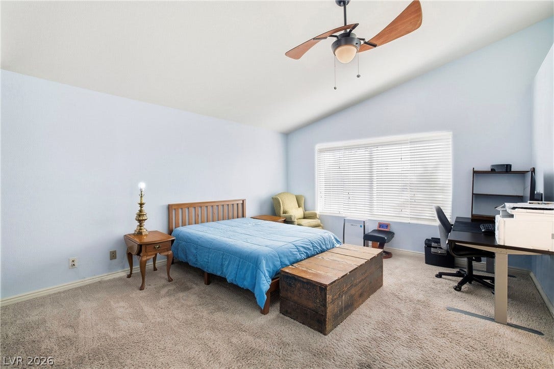 A vaulted ceiling and carpeted flooring define this airy primary bedroom space.