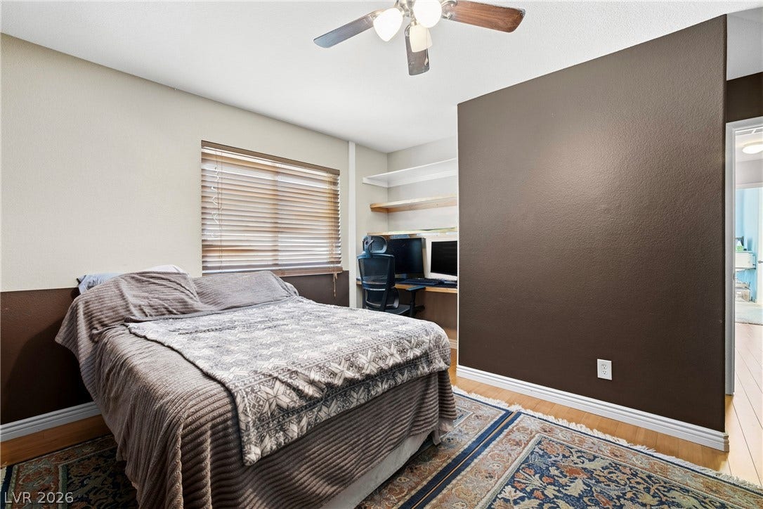 Rich hardwood flooring anchors this versatile bedroom featuring a built-in study nook and shelving.