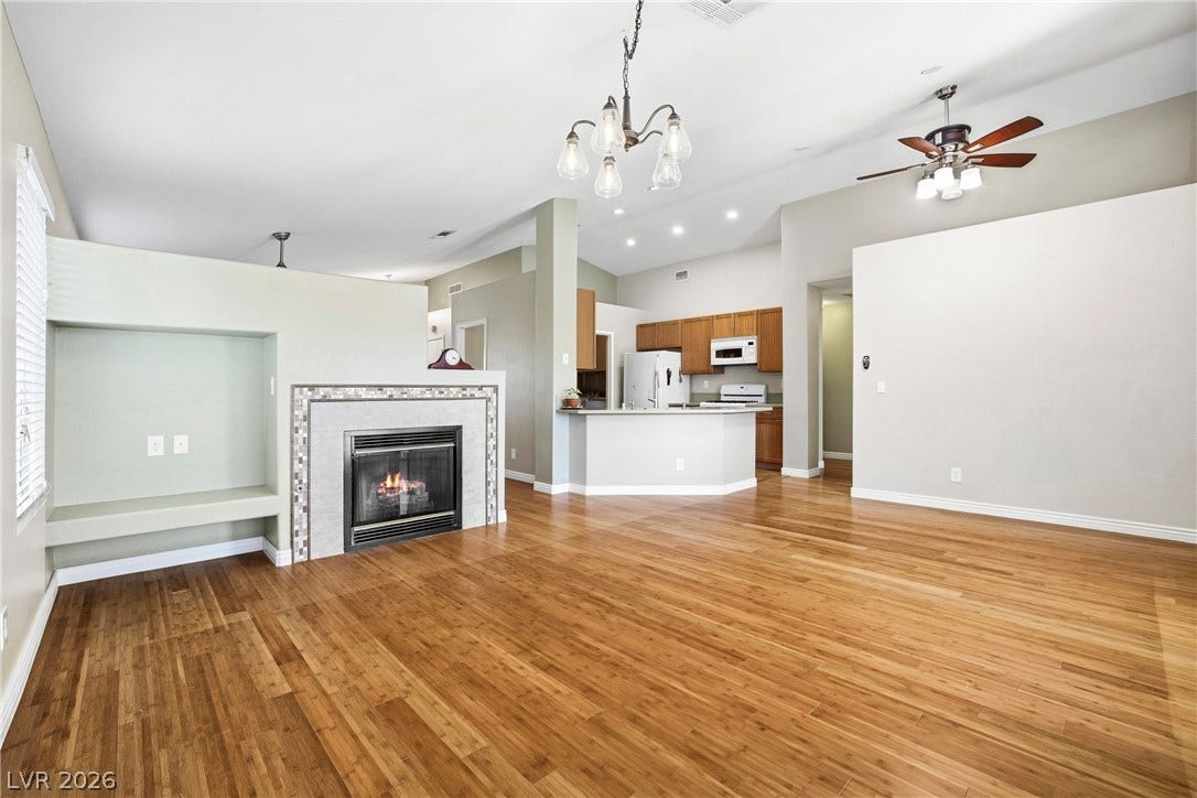 Rich hardwood floors and a tiled fireplace define this airy, open-concept living space.