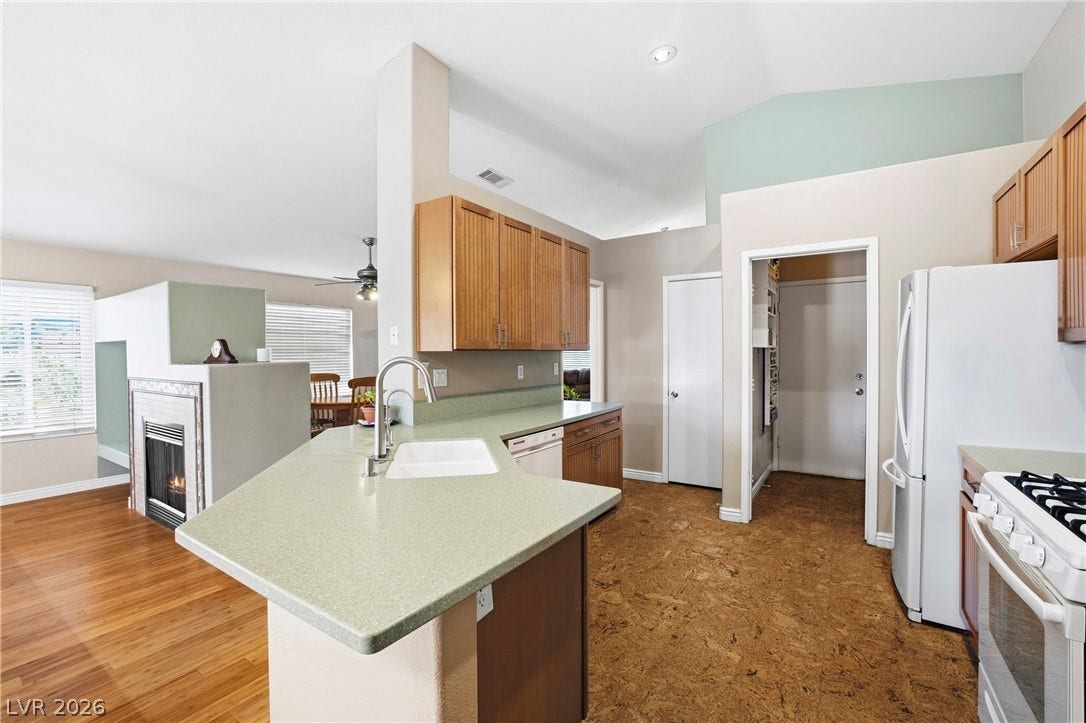 Vaulted ceilings and wood-style flooring enhance this open-concept kitchen layout.