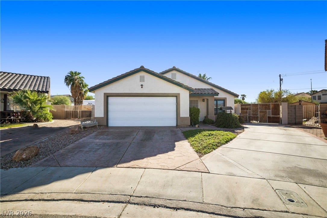 Classic stucco exterior showcases a tile roof and a spacious front-facing garage with concrete driveways.