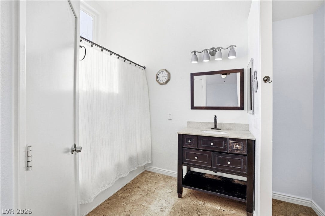 An elegant dark wood vanity brings character to this bright primary bathroom space.