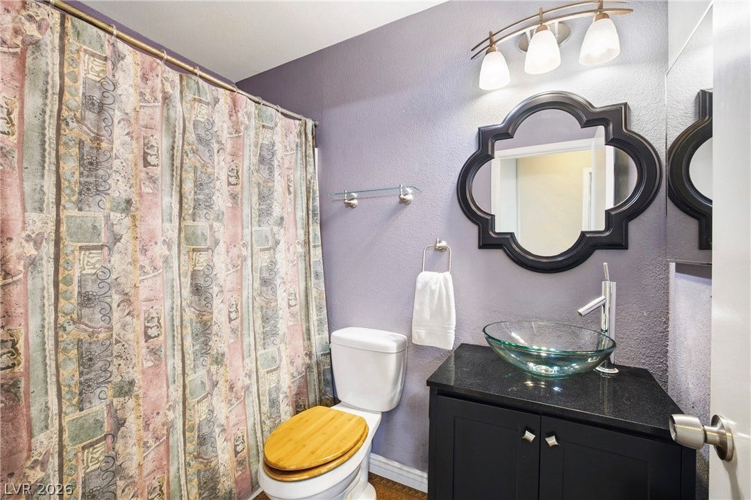 An elegant glass vessel sink crowns the dark vanity in this modern bathroom.