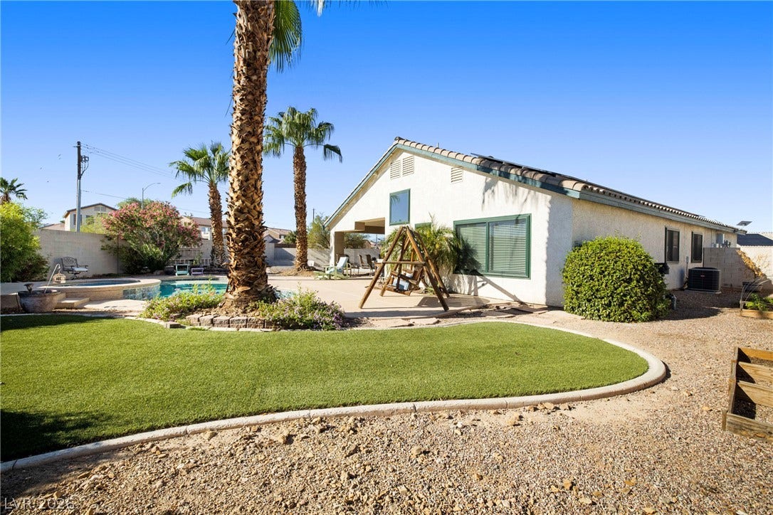 A tiled roof and stucco exterior look out over the pool and grassy lawn.