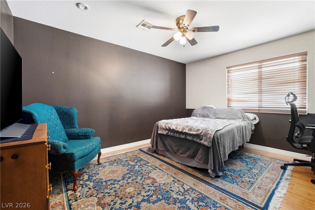 Hardwood flooring and ceiling fan enhance this versatile bedroom space.