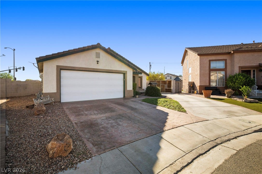 A spacious driveway leads to the attached garage under clear blue desert skies.