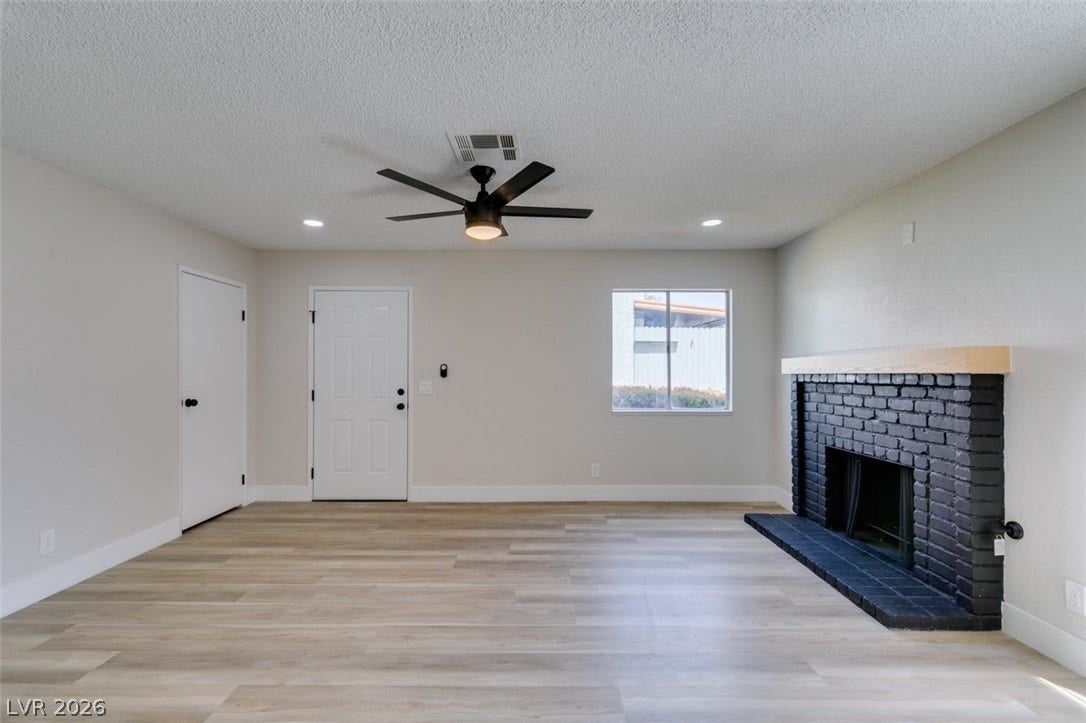 3638 Villa Knolls East Drive, Las Vegas, NV 89120 Smooth wood-look flooring and a contrasting brick fireplace anchor this versatile living space.