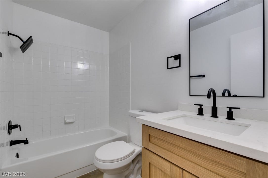 3638 Villa Knolls East Drive, Las Vegas, NV 89120 Crisp white tiling pairs with a light wood vanity and matte black hardware.