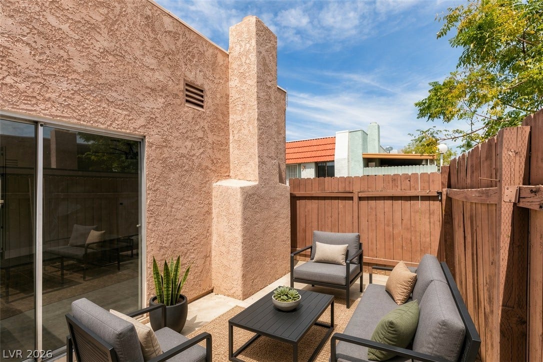 3638 Villa Knolls East Drive, Las Vegas, NV 89120 Virtually Staged A secluded backyard patio enclosed by tall wooden fencing features textured stucco walls.
