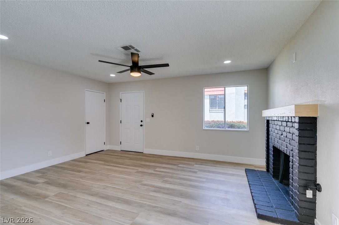 3638 Villa Knolls East Drive, Las Vegas, NV 89120 Smooth wood-look flooring and a modern brick fireplace frame this inviting living space.