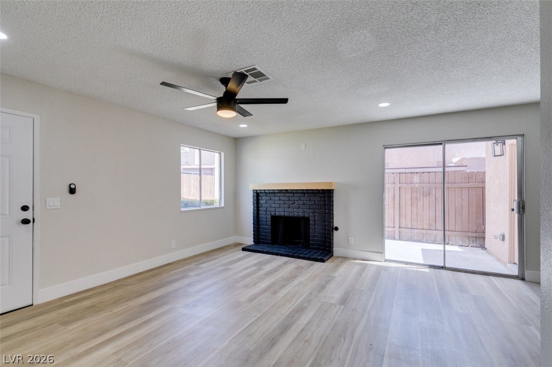 3638 Villa Knolls East Drive, Las Vegas, NV 89120 Smooth wood-look flooring and a brick fireplace anchor this welcoming, open living space.