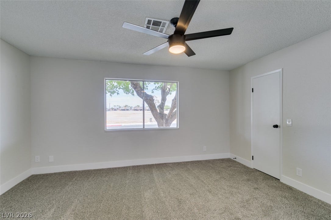 3638 Villa Knolls East Drive, Las Vegas, NV 89120 Soft carpeting pairs with neutral walls and a large window framing leafy outdoor views.