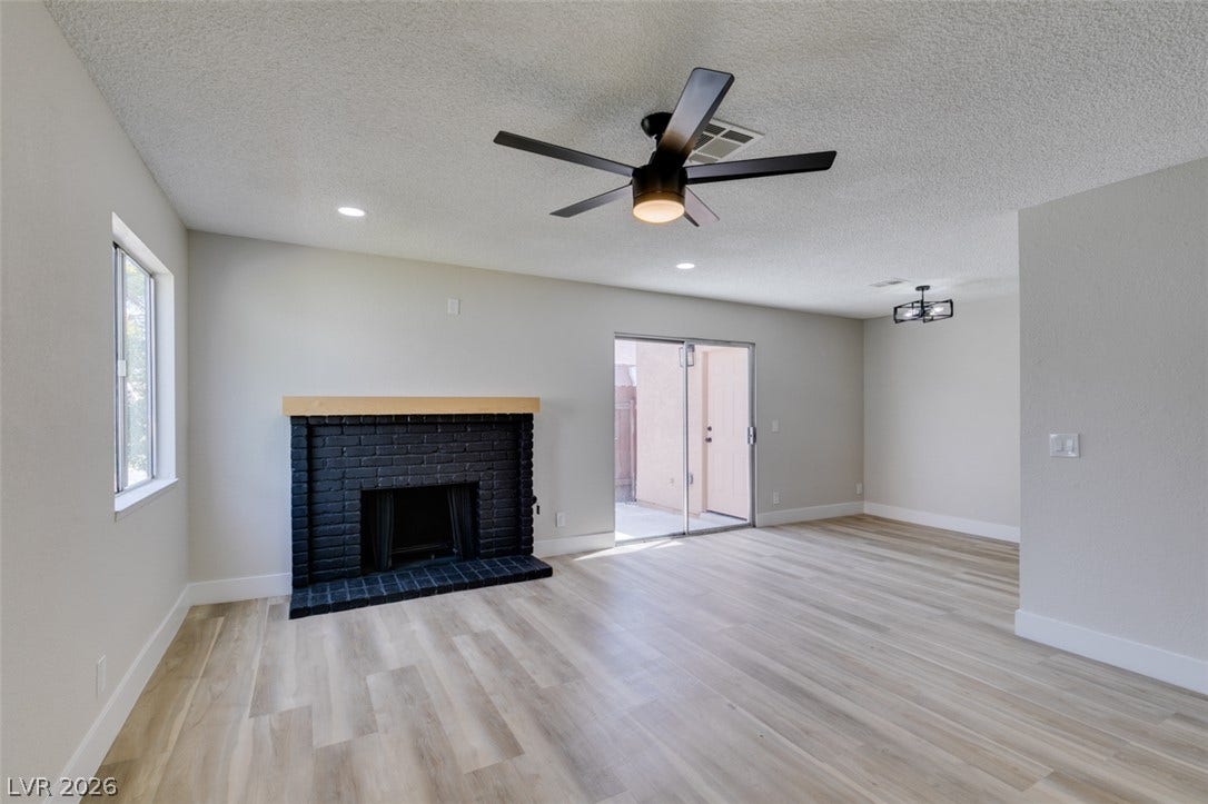 3638 Villa Knolls East Drive, Las Vegas, NV 89120 Smooth wood-look flooring and a brick fireplace anchor this airy living space with outdoor access.